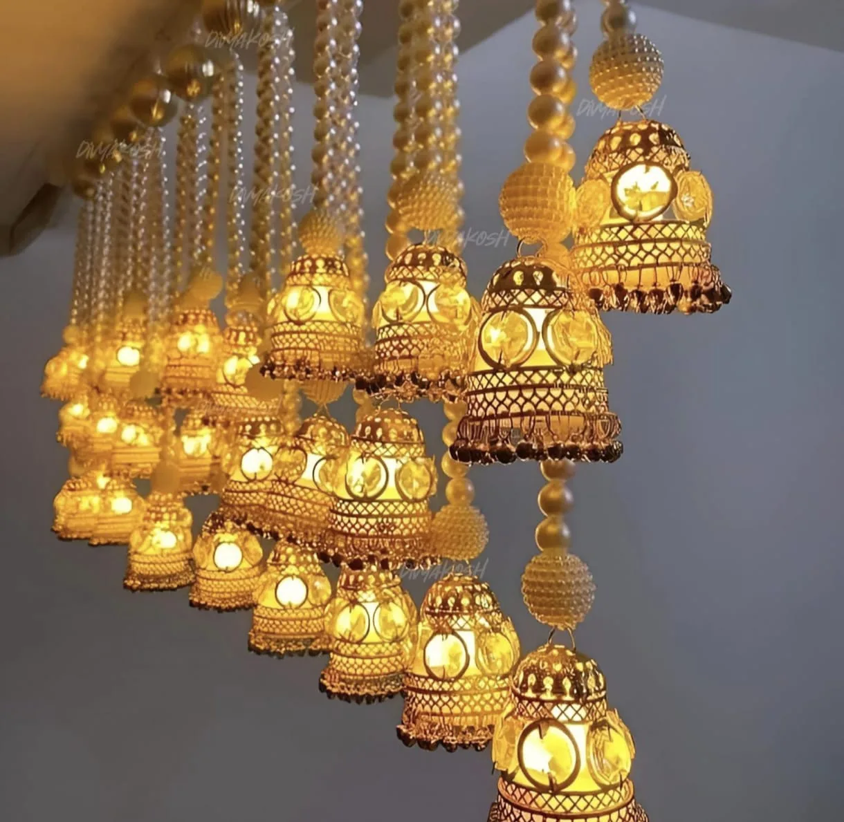 Jhumka Metal Hanging Lamp with Lights (Set of 2) | Youteek 2 Jhumka metal hanging lamp, set of 2. Golden finish with pearl strings, 3 battery-operated light strings in each. Cage about 4 inches, length about 19 inches. PVC box packing. golden jhumka lamp with pearl strings